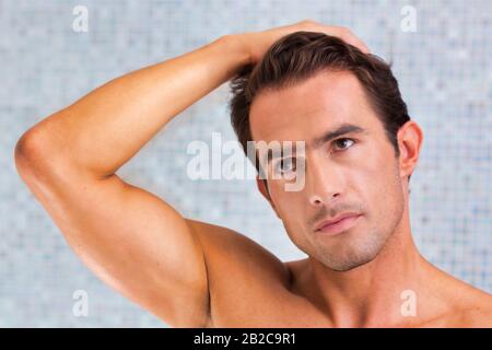 Uomo attraente che controlla il suo volto nello specchio del bagno Foto Stock