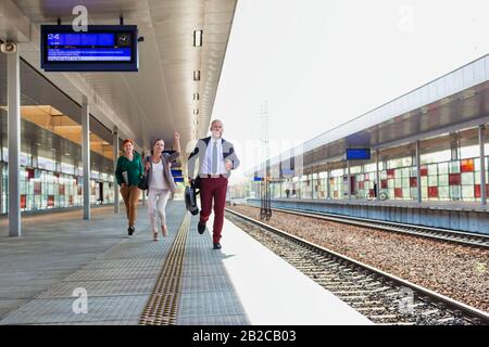 Ritratto di uomini d'affari che corrono per prendere il treno in stazione Foto Stock