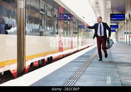 Ritratto di uomini d'affari che corrono per prendere il treno in stazione Foto Stock