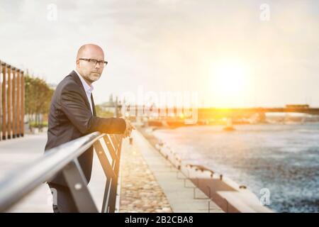 Ritratto di uomo d'affari maturo pensieroso appoggiato su ringhiera Foto Stock