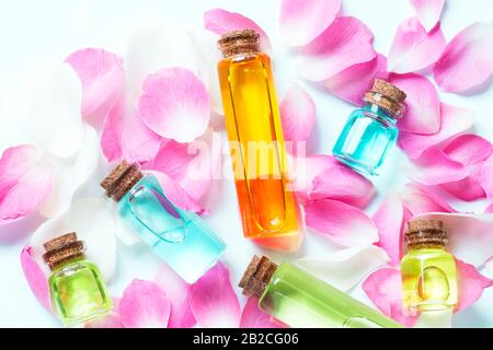 Essenza di bottiglie di olio di colore rosa con petali di rosa Foto Stock