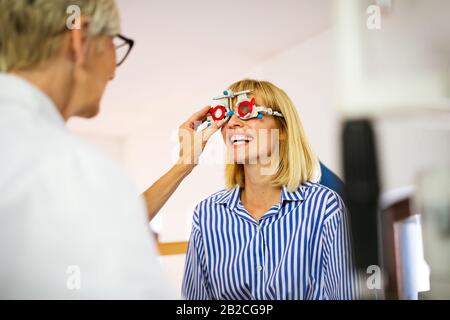 Donna Senior all'ottico optometrista esame paziente nella moderna Oftalmologia Clinica Foto Stock