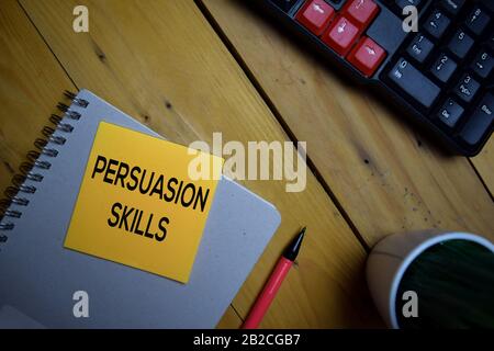 Le Abilità di persuasione scrivono su una nota appiccicosa isolata su sfondo di legno. Foto Stock