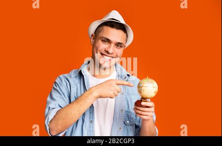 Giovane turista che tiene il globo, indicando la destinazione desiderabile del viaggio Foto Stock