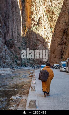 L'uomo solitario che viaggia attraverso le famose gole di Toudgha, alla ricerca di un trasporto che lo porta alla città di Tinghir (Marocco) Foto Stock