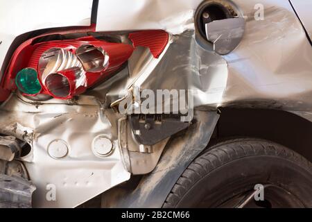 Parte posteriore di un veicolo dopo un incidente, con diverse parti rotte e con lo pneumatico sgonfio. Concetto di sicurezza stradale e assicurazione auto Foto Stock