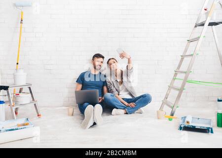 Felice coppia prendendo selfie mentre sceglie il progetto sul laptop Foto Stock