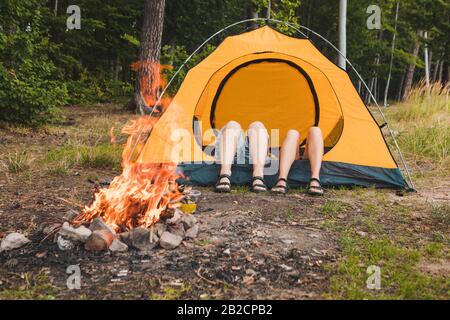 coppia sdraiato in tenda vicino al fuoco del campeggio. vacanza attiva Foto Stock