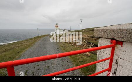 Cancello di metallo rosso chiuso che conduce al faro e cottage guardacoste in Irlanda al faro di Rinraawros Point sull'Isola di Arranmore, County Donegal. Foto Stock