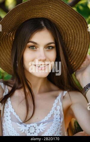 La ragazza estiva ritratto in verde. Giovane bella donna dai capelli scuri gode della freschezza del giardino estivo. Idea e concetto di vacanza estiva in Foto Stock