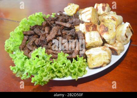 Porzione di carne alla griglia sul piatto con salsa di prezzemolo e pane. Piatto del ristorante. Foto isolata su sfondo nero. Foto Stock