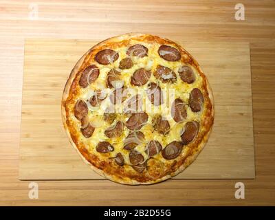 Pizza fatta in casa con pepe, formaggio e cipolla. Foto scattata a casa in australia, vista dall'alto verso il basso, primo piano. Tavolo in legno e illuminazione artificiale. Foto Stock