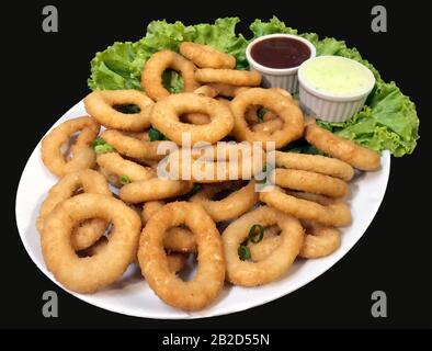 Anelli Di Cipolla fritti, con lattuga e salse. Chiudi la foto. Piatto brasiliano in un ristorante Foto Stock