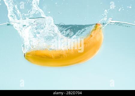 Banana dolce in acqua spruzzi su sfondo blu Foto Stock