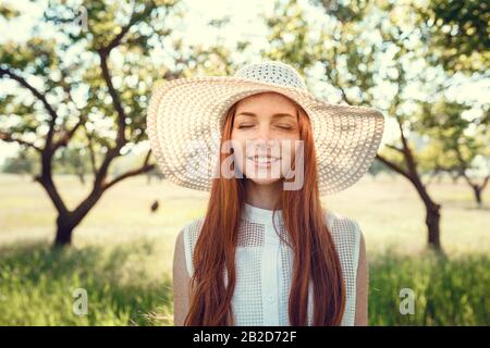 Bella fotoprofessione di matrimonio. La giovane sposa carina in un elegante abito in pizzo bianco nel mezzo degli alberi in un grande giardino verde sulla weathery sunn Foto Stock