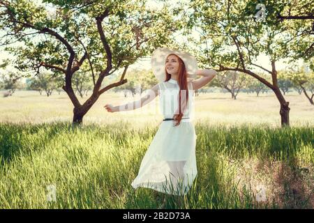 Bella fotoprofessione di matrimonio. La giovane sposa carina in un elegante abito in pizzo bianco nel mezzo degli alberi in un grande giardino verde sulla weathery sunn Foto Stock