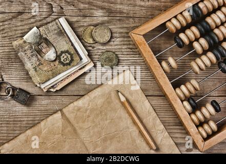 Le vecchie banconote e monete e abacus su un tavolo di legno Foto Stock