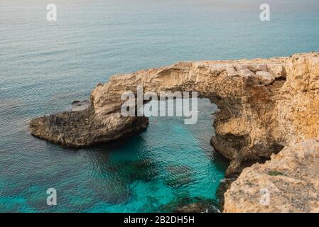 Ponte di pietra per gli amanti Love Bridges sul mare vicino alle montagne sull'isola di Ayia Napa Cipro Foto Stock