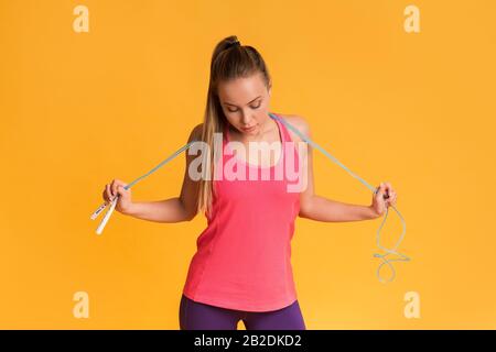 Ragazza che posa con corda di salto e che guarda il suo corpo di misura Foto Stock