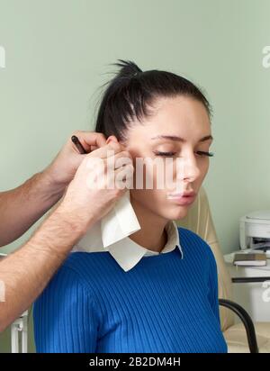 Attento medico che fa l'esame dell'orecchio di donna graziosa Foto Stock