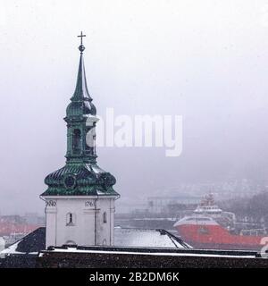 Inverno A Bergen, Norvegia. Nevicando alla chiesa di Nykirken. Vista verso il porto di Vaagen, Bergenhus e Sandviken. Foto Stock