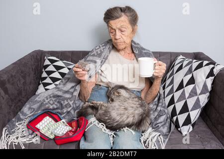 Donna anziana che prende la pillola a casa. Donna anziana con la sua compressa di medicina. Ll paziente anziano che tiene le pillole di medicamento nelle mani. Medicina e. Foto Stock