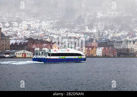 Inverno A Bergen, Norvegia. Nevicando pesante. Vista dal vecchio porto della città, Vaagen. Architettura anseatica dell'UNESCO a Bryggen. Passeggero ad alta velocità Foto Stock