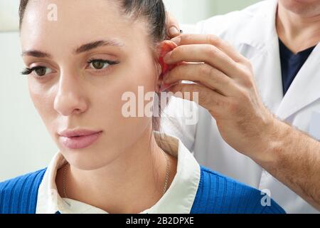 Il chirurgo plastico esamina l'orecchio del paziente prima della chirurgia plastica Foto Stock