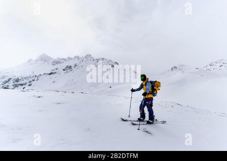 Scialpinismo nella neve in nebbia, dietro le cime delle gole in nubi, Wattentaler Lizum, Alpi Tuxer, Tirolo, Austria Foto Stock