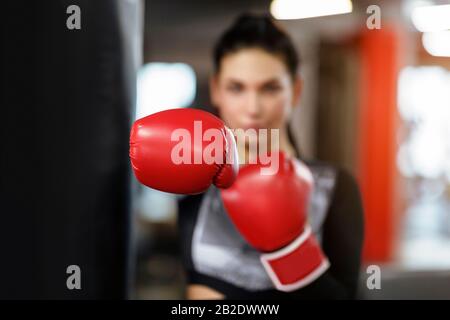 Classe di difesa personale. Giovane sportivo femminile in palestra, concentrarsi sul guanto da boxe Foto Stock