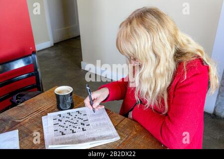 Donna che fa cruciverba nella caffetteria Foto Stock