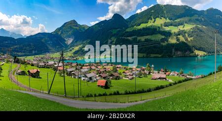 Villaggio Svizzero di Lungern con le sue case tradizionali e la vecchia chiesa torre Alter Kirchturm lungo il lago Lungerersee, cantone di Obvaldo, Svizzera Foto Stock