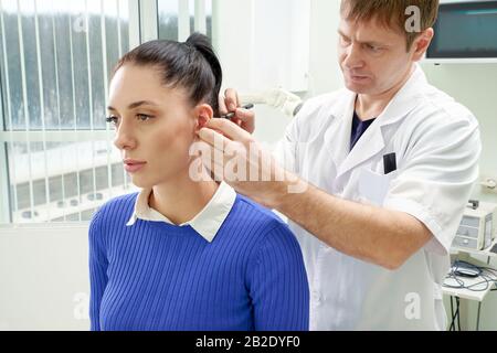 Il chirurgo plastico esamina l'orecchio del paziente prima della chirurgia plastica Foto Stock