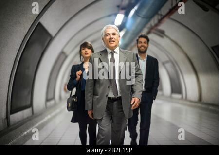 Tre colleghi di affari sorridenti che camminano con fiducia in un tunnel della metropolitana Foto Stock