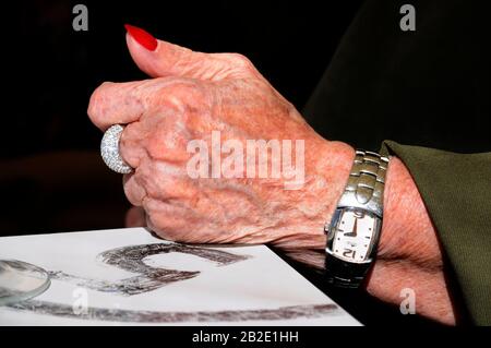 La mano della nonna è chiusa sul tavolo. Nonna che indossa un grande anello d'argento e un orologio. Vecchie mani femminili sul tavolo, Foto Stock