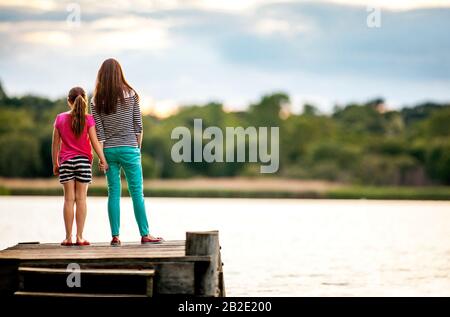 Madre e figlia che si affacciano su un lago da un molo Foto Stock