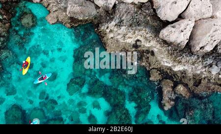 Vista di un drone da un drone le persone sono kayak in mare vicino alle montagne in una grotta con acqua turchese sull'isola di Cipro Ayia Napa Foto Stock