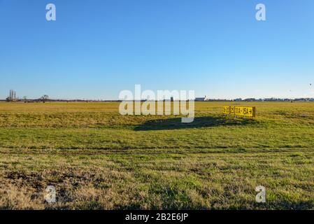 Campo d'erba e vecchio numero di segnale giallo sul campo d'atterraggio del parco Tempelhof, aeroporto precedente, a Berlino, Germania Foto Stock