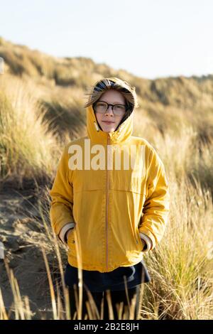 Tween in piedi in dune coperte di erba spiaggia sulla costa della California Foto Stock