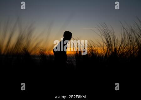 Silhouette di escursioni teen lungo le dune della California del Nord al tramonto Foto Stock