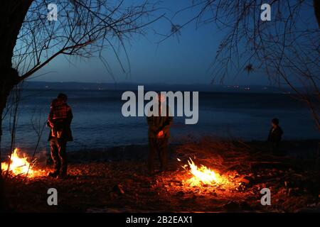 Lesbo, Grecia. 2nd Mar, 2020. I migranti e i rifugiati giunti dalla Turchia cercano di riscaldarsi con il fuoco di Skala Sikaminias, nell'isola di Lesvos, in Grecia, il 2 marzo 2020. La Grecia ha adottato una posizione più dura e sta trattando la sfida migratoria come una questione di sicurezza nazionale, ha affermato lunedì il ministro degli interni Takis Theodorikakos. Credit: Marios Lolos/Xinhua/Alamy Live News Foto Stock