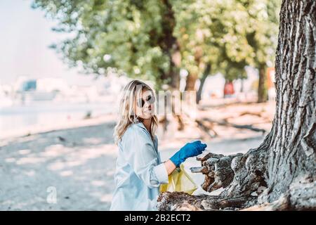 Ragazza raccogliere rifiuti dal parco. Raccoglie la lettiera in un sacchetto per la spazzatura Foto Stock