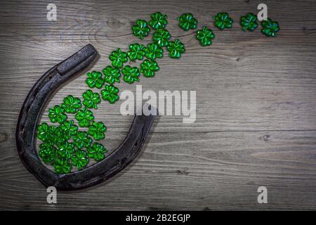 Concetto di giorno di San Patrizio - ferro di cavallo arrugginito con shamrock su sfondo di legno. Simbolo di festa di San Patrizio. Fascino fortunato. Vista dall'alto, spazio di copia. Foto Stock