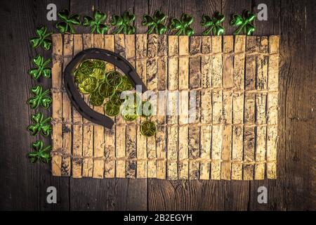 Sfondo con arrugginito ferro di cavallo e foglie di trifoglio e monete su legno rustico. Simbolo di festa di San Patrizio. Fascino fortunato. Vista dall'alto, spazio di copia. Foto Stock