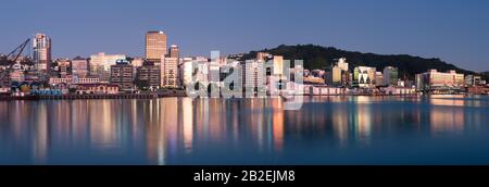 Wellington, gli edifici della città neozelandese e lo skyline si riflettono nel porto all'alba in una perfetta mattinata estiva. Wellington è la capitale della Nuova Zelanda. Foto Stock