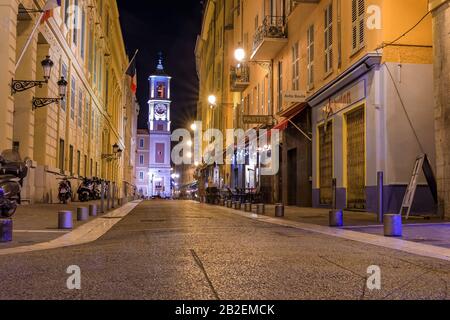 Nizza, Francia - 2 giugno 2019: Vista notturna della torre dell'orologio Caserne Rusca e di una strada con ristoranti e negozi nella città vecchia Vieille Ville Foto Stock