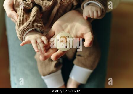 il bambino tiene un succhietto nelle braccia della madre Foto Stock