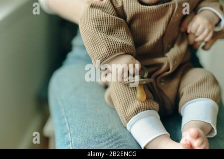 il bambino tiene un succhietto nelle braccia della madre Foto Stock