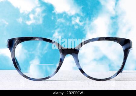 Occhiali da vista con Bifocals e Cornice blu nero smudged agaist un cielo blu e nuvoloso Foto Stock