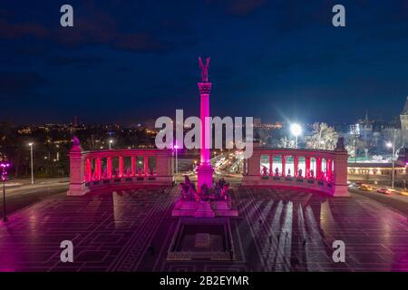 Budapest, Ungheria - veduta aerea del drone della famosa Piazza degli Eroi (Hosok tere) illuminata da luci viola e rosa uniche di notte Vajdahunyad Castello A. Foto Stock